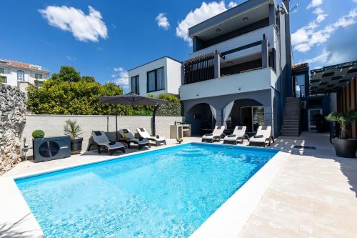 a swimming pool in front of a house at Villa Paula s grijanim bazenom in Crikvenica