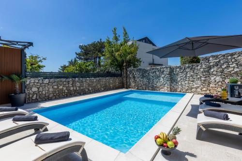 a swimming pool with chairs and an umbrella at Villa Paula s grijanim bazenom in Crikvenica