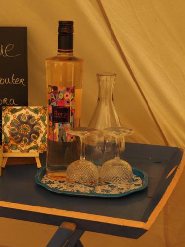 a bottle of alcohol and two glasses on a table at Glamping Tent Celte du Morvan, Vrij in de Natuur in La Tagnière
