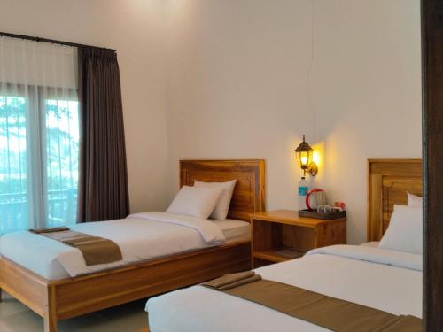 a bedroom with two beds and a window at Nan Bungalows Tetebatu in Tetebatu