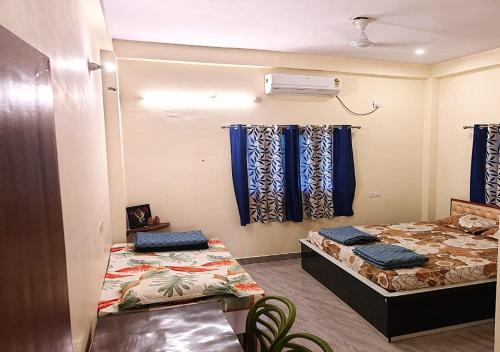 two beds in a room with blue curtains at Nature Homestay in Varanasi
