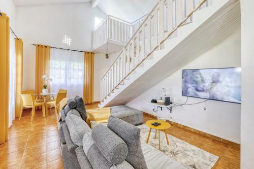 a living room with a couch and a tv at La Villa Des Lys avec jacuzzi in Saint-Denis