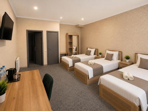 a hotel room with two beds and a desk at Boston Hotel Tashkent in Yakkasaray