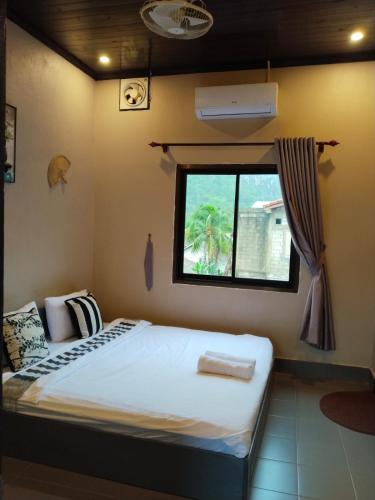 a bed in a room with a window at Vinla Guesthouse & Backpackers Hostel in Nongkhiaw