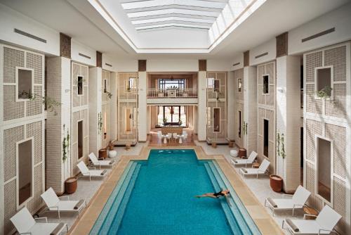 a pool in a building with chairs and a person laying on the floor at Fairmont Royal Palm Marrakech in Marrakech