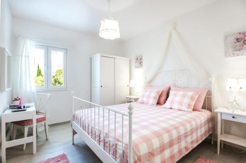 a white bedroom with a white bed with pink pillows at Ksenija Apartments in Tučepi