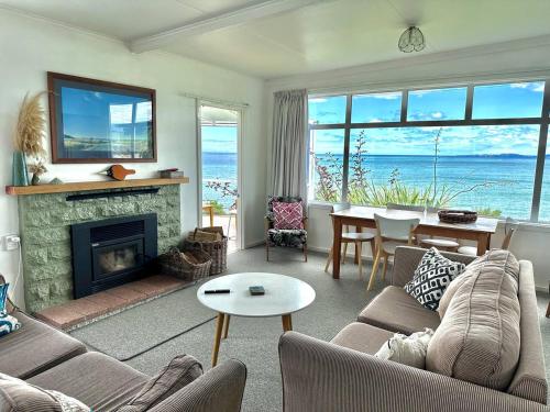 a living room with a couch and a fireplace and a table at Kakanui Ocean Views in Kakanui