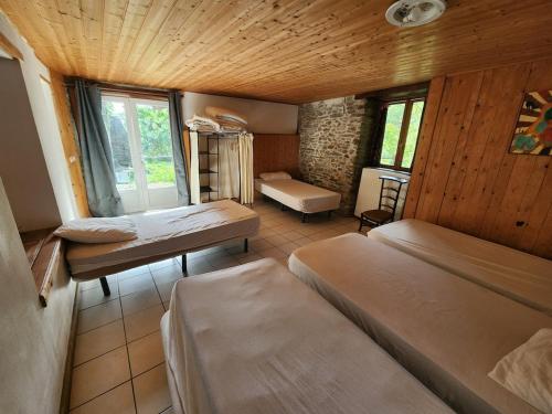 a room with three beds in a room with a window at Grand Gite des Jourdets in Lairière