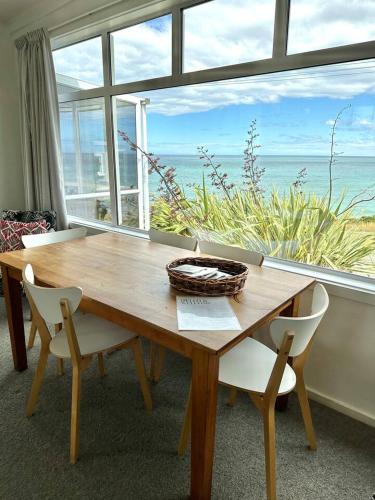 a wooden table with chairs and a large window at Kakanui Ocean Views in Kakanui