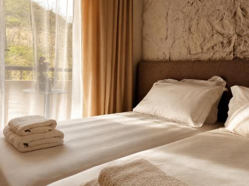 Ein Bett mit darauf liegenden Handtüchern neben einem Fenster in der Unterkunft Blue Mill Resort, Sarande in Mesopotam