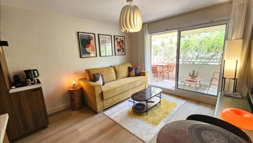 a living room with a couch and a table at Studio Golfe Juan bord de mer - parking & piscine in Vallauris