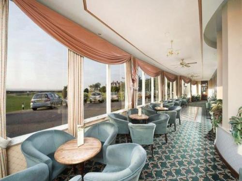 a dining room with chairs, tables, and umbrellas at Dornoch Hotel 'A Bespoke Hotel' in Dornoch