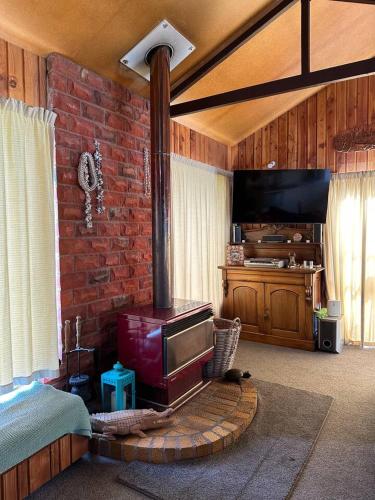 a living room with a brick wall with a wood stove at Kakanui Surf Bach in Kakanui