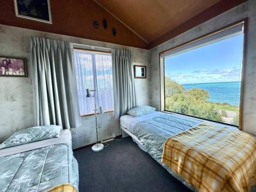 a bedroom with two beds and a large window at Kakanui Surf Bach in Kakanui