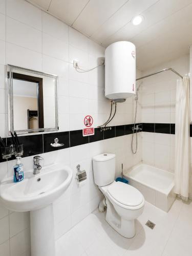 a white bathroom with a toilet and a sink at Boston Hotel Tashkent in Yakkasaray