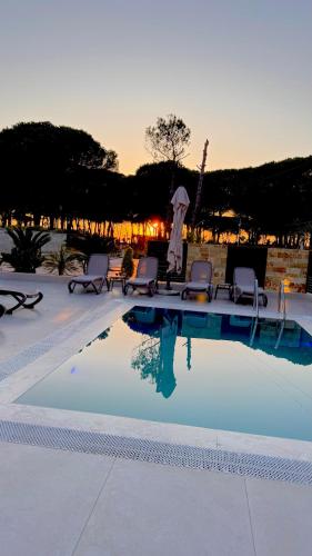 a pool with chairs and a sunset in the background at Swiss Villa Qerret in Golem