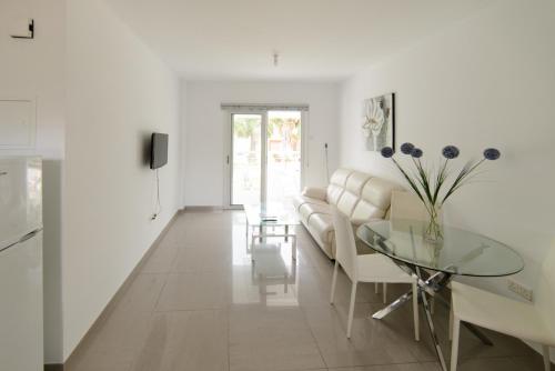 アヤナパにあるKatalimata Courtの白いリビングルーム(ソファ、ガラステーブル付)