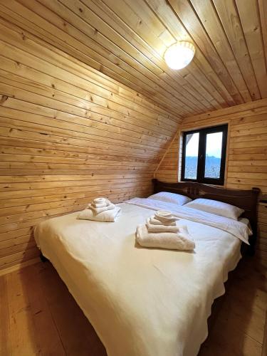a bed in a wooden room with towels on it at Сади Вітрів in Oriv