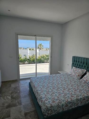 a bedroom with a bed and a large window at Penthouse sarra in Kelibia