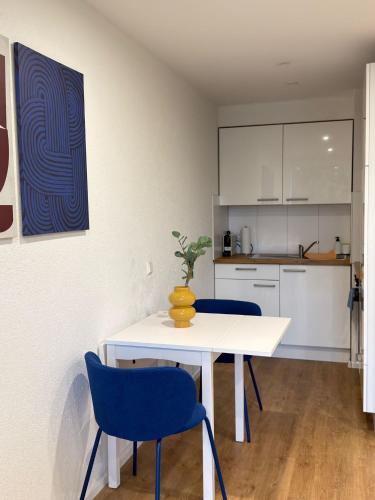 a kitchen with a white table and two blue chairs at City Apartment in Lörrach