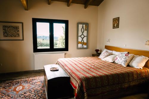 a bedroom with a bed with a window and a rug at The Englishman's Villa Evia in Perivólia