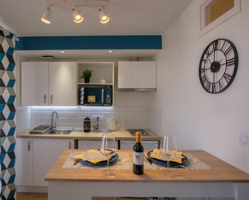 a kitchen with a counter with a clock on the wall at Le cottage roannais in Roanne
