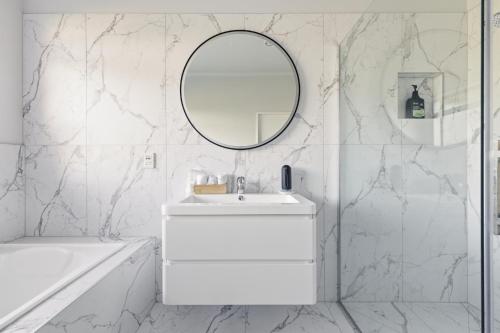 a white bathroom with a sink and a mirror at McLaren Lake View in Tauranga
