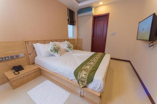 a bedroom with a bed with white sheets and a television at Hathaa Beach Maldives in Hulhumale