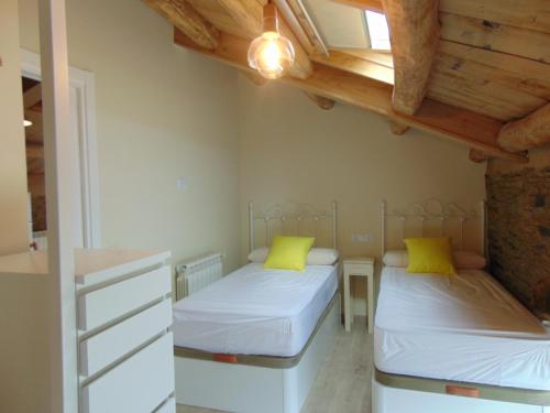 two beds in a small room with wooden ceilings at Casa Venancio in Trabada
