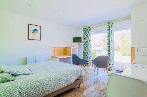 a bedroom with a bed and chairs and a window at GITES EN BAIE DE SOMME - Maison Nolette in Noyelles-sur-Mer