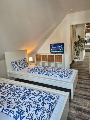 a bedroom with two beds and a tv on the wall at Ferienwohnung bei Nebel in Mandelsloh in Neustadt am Rübenberge