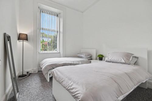 two beds in a white room with a window at 173 Newark Street, Greenock in Greenock
