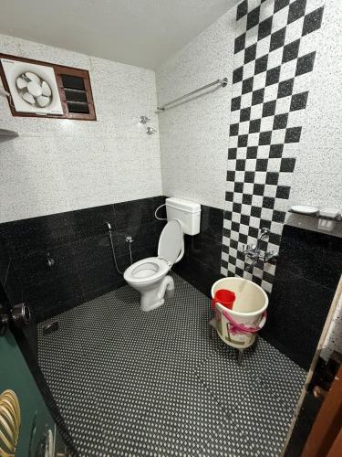 a bathroom with a toilet and a checkered wall at Deepa HomeStay in Dharmastala
