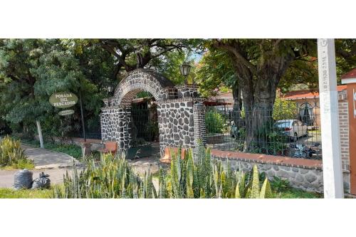 a stone archway in a park with a tree at Capital O Posada Del Pescador Jocotepec in Chapala