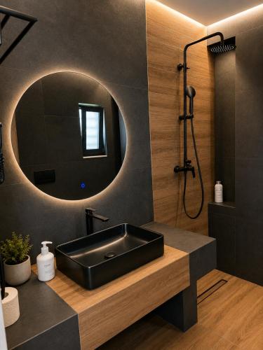 ein Badezimmer mit schwarzem Waschbecken und Spiegel in der Unterkunft Mat Suites in Lachania
