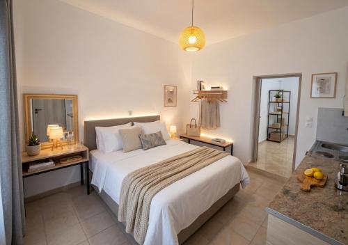 a bedroom with a large white bed and a desk at Artemis Studios - Pool and garden in Koskinou
