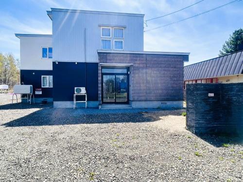 a white and blue house with a chair in front of it at Villa和心 in Asahikawa
