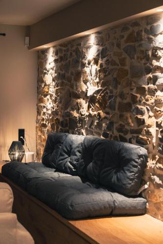 a couch sitting in front of a stone wall at Stone Barn Menil Sauna & Nordic Bath in Ardennes in Hotton