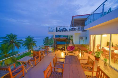a balcony with tables and chairs and the ocean at Hathaa Beach Maldives in Hulhumale