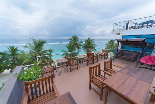 a balcony with tables and chairs and the ocean at Hathaa Beach Maldives in Hulhumale