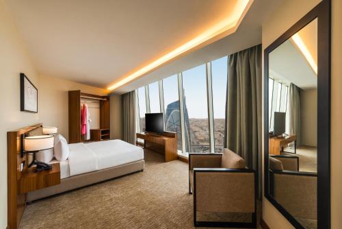 a hotel room with a bed and a large window at HDB Financial District in Riyadh