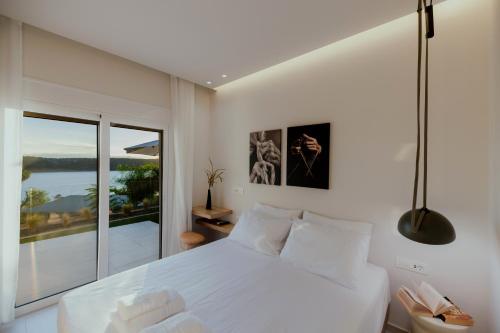 a bedroom with a white bed and a large window at Lefka Apartment in Vivari