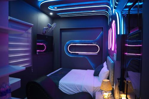a bedroom with a bed in a room with neon lights at Haven Hotel in Ho Chi Minh City