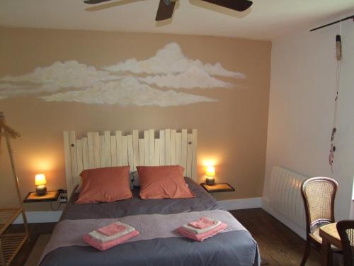 a bedroom with a bed with a cloud mural on the wall at Au Bois de la Grave in Luzech