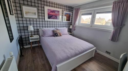 a small bedroom with a bed and two windows at Innisfail Edi - double room with private bathroom in Edinburgh