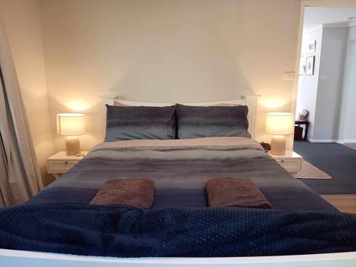a bedroom with a large bed with two lamps at Beach & Forest Stay in Port Arthur