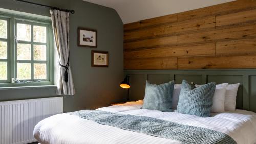 a bedroom with a large bed with a wooden headboard at The Poacher Inn in Upton Grey