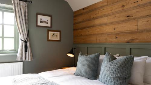 a bedroom with a bed with a large wooden headboard at The Poacher Inn in Upton Grey