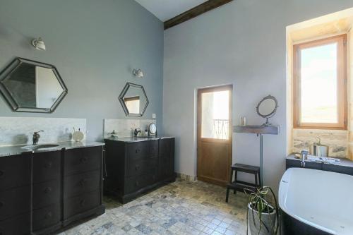 a bathroom with two sinks and a tub and a mirror at La Vie de Château, proche Lyon in Bessenay