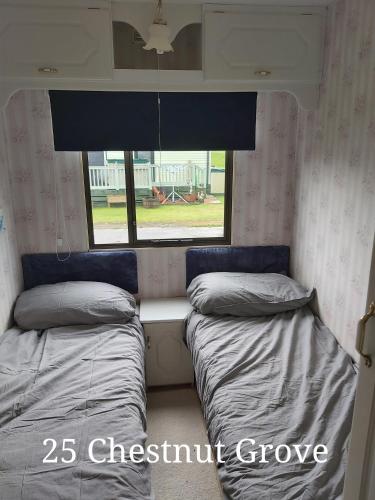 two beds in a room with a window at 25 Chestnut Grove in Kirkcolm